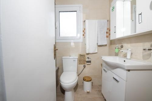 a white bathroom with a toilet and a sink at City walls sea view in Corfu Town