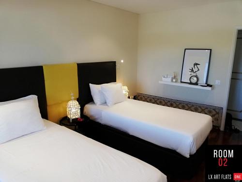 a hotel room with two beds with white sheets at Lx Art Flats | Flat Two in Lisbon