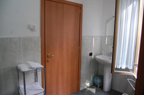 a bathroom with a wooden door and a sink at Affittacamere Derby in Ranica