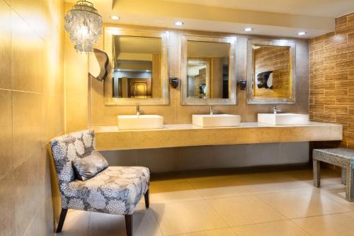 a bathroom with three sinks and a chair and mirrors at Gran Casa Xalisco in Guadalajara