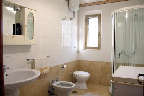 e bagno con servizi igienici, lavandino e doccia. di Villa Robinia a Massafra