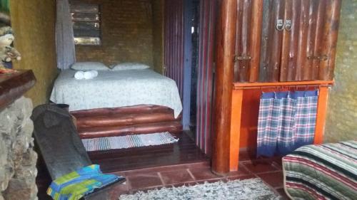 a bedroom with a bed and a chair in a room at A Casinha Pequenina in Monte Verde