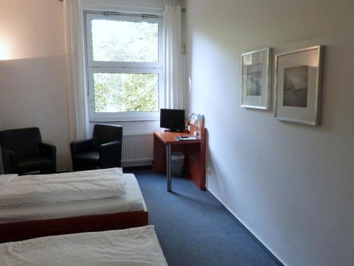 ボンにあるCJD Bonn Castellのベッド2台、デスク、窓が備わるホテルルームです。