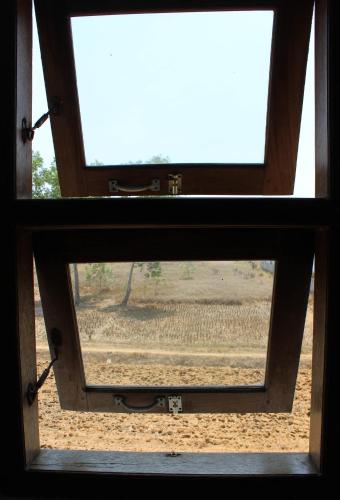 a view through a window of a field at Harrys Oceanhouse 2 Pacitan in Pacitan