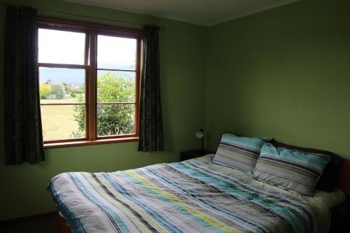 a green bedroom with a bed and a window at Batch with a View in Te Anau