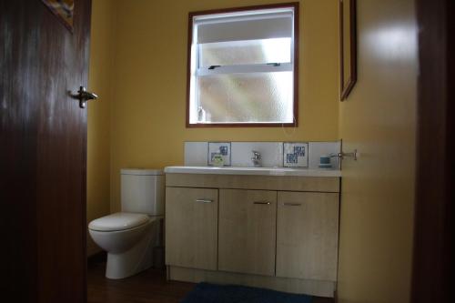 a bathroom with a toilet and a sink and a mirror at Batch with a View in Te Anau