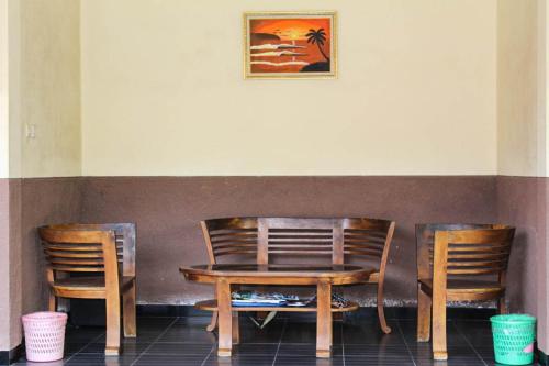 a wooden table and two chairs and a table and a picture at Harrys Oceanhouse 2 Pacitan in Pacitan