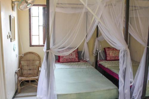 a bedroom with two beds with mosquito nets at Harrys Oceanhouse 2 Pacitan in Pacitan