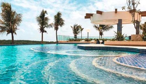 a swimming pool with palm trees and a building at Salinas Park Resort in Salinópolis