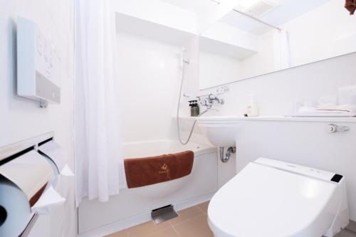a white bathroom with a toilet and a sink at Nipponbashi Crystal Hotel in Osaka