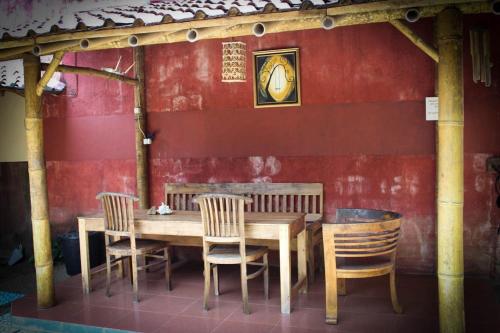 einen Holztisch und Stühle vor einer roten Wand in der Unterkunft Harrys Oceanhouse 2 Pacitan in Pacitan