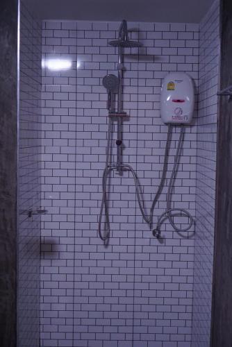 a white tiled bathroom with a shower with a soap dispenser at S.S.Hotel Nangrong in Nang Rong