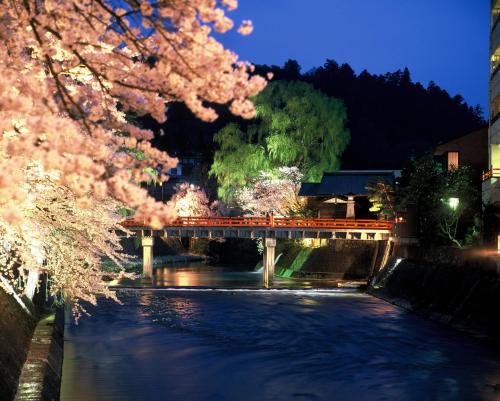 a bridge over a river at night with pink flowers at BEYOND HOTEL Takayama 2nd in Takayama