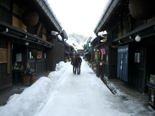 a person walking down a snow covered street at BEYOND HOTEL Takayama 2nd in Takayama