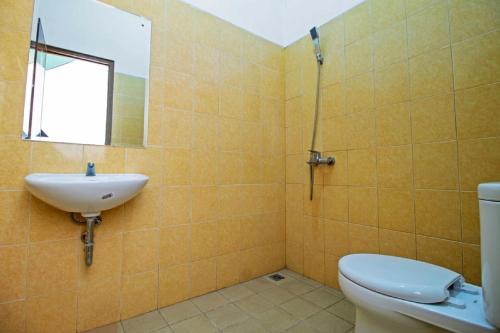 uma casa de banho com um lavatório, um WC e um espelho. em RedDoorz Syariah near Mercu Buana University em Jakarta