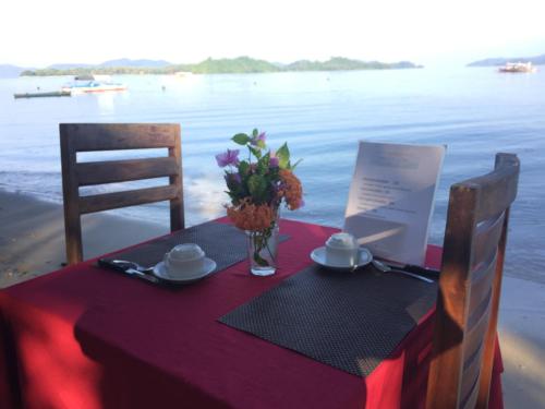 a table with a purple table cloth and flowers on the beach at Prince John Beachfront Eco Bungalows and Restaurant in San Vicente