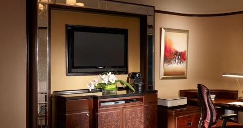 a hotel room with a flat screen tv and a desk with flowers at Shangri-La Kuala Lumpur in Kuala Lumpur