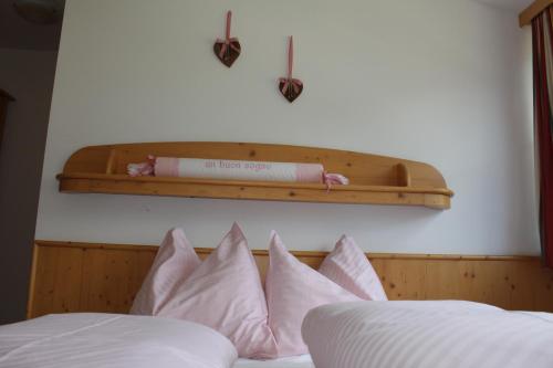 a bed with pink pillows and a shelf above it at Appartementhaus Lechnerhof in Brunico