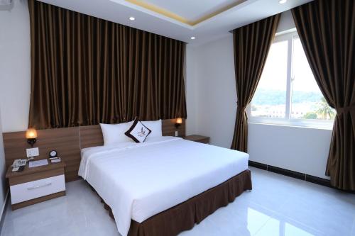 a bedroom with a large bed and a large window at Phung Hung Boutique Hotel in Phu Quoc