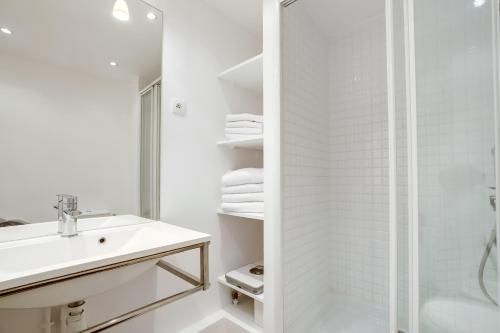 une salle de bain blanche avec un lavabo et une douche dans l'établissement Unit 010 Cherche Midi 19, à Paris