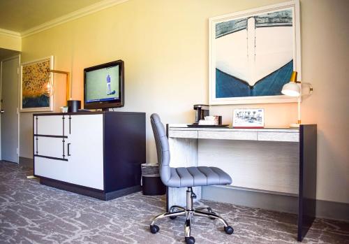a room with a chair and a desk and a television at Beachside Inn in Santa Barbara
