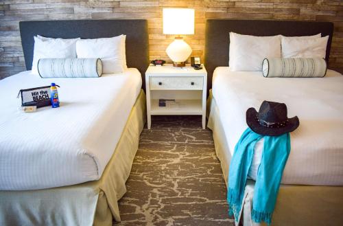 a hotel room with two beds with a hat on it at Beachside Inn in Santa Barbara