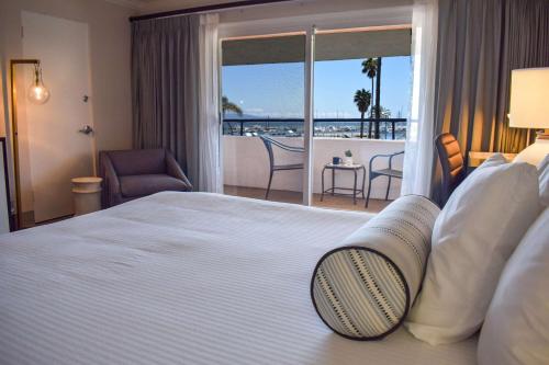 a hotel room with a bed with a view of a balcony at Beachside Inn in Santa Barbara