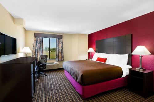 um quarto de hotel com uma cama e uma televisão de ecrã plano em Baymont Inn & Suites by Wyndham Mukwonago em Mukwonago