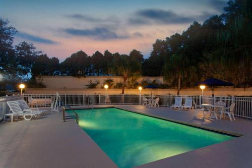 a swimming pool with chairs and a table and an umbrella at Microtel Inn and Suites by Wyndham - Lady Lake/ The Villages in The Villages