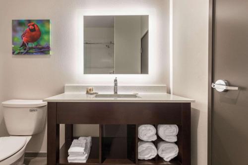 ein Badezimmer mit einem Waschbecken und einem Stapel Handtücher in der Unterkunft La Quinta Inn and Suites by Wyndham Bloomington in Bloomington