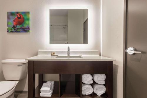 a bathroom with a sink and a pile of towels at La Quinta Inn and Suites by Wyndham Bloomington in Bloomington