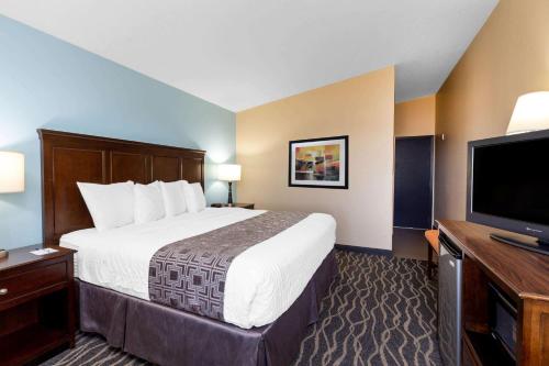a hotel room with a bed and a flat screen tv at Baymont by Wyndham Tri-Cities/Kennewick WA in Kennewick