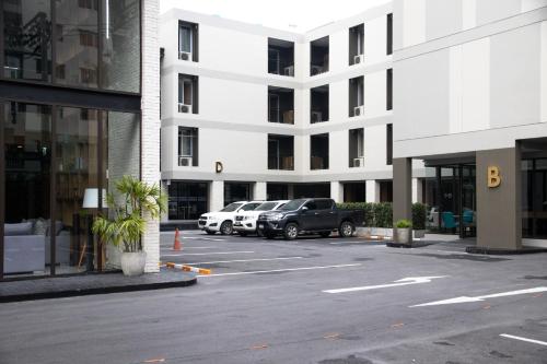 a parking lot with cars parked in front of a building at B Stay Hotel in Bangkok