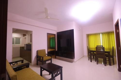 a living room with a tv and a table and chairs at Kfour Apartment & Hotels Private Limited in Madurai