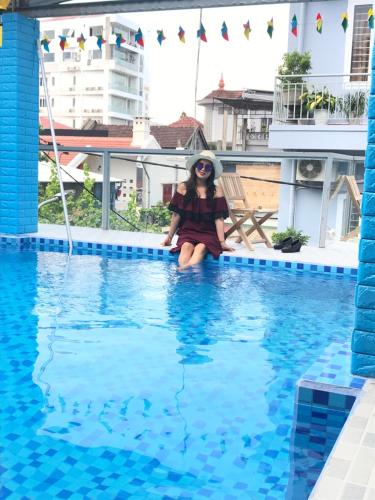 a little girl sitting on the edge of a swimming pool at Poetic Hue Hotel & Spa in Hue