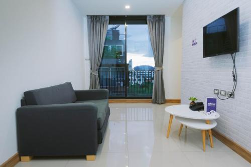 a living room with a couch and a tv and a table at Kokotel Bangkok Sukhumvit 50 in Bangkok