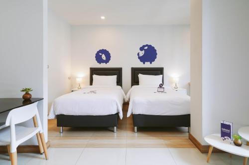 a hotel room with two beds and a table at Kokotel Bangkok Sukhumvit 50 in Bangkok