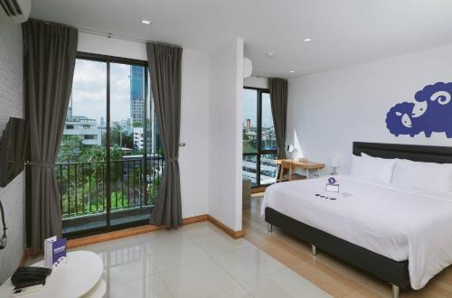 Kokotel Bangkok Sukhumvit 50 - SHA Extra Plus في بانكوك: غرفة نوم بسرير كبير ونافذة كبيرة