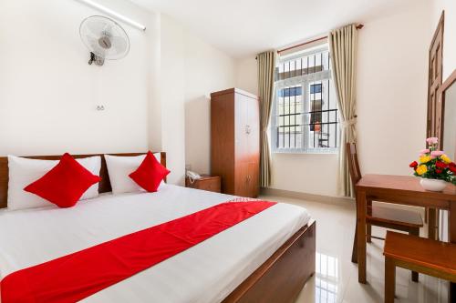 a bedroom with a bed with red pillows and a window at Jupiter Hotel in Vung Tau