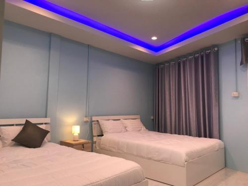 a bedroom with two beds and a blue lighting at Blue House Hat Yai in Hat Yai