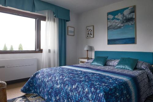 a bedroom with a bed with a blue blanket and a window at Villa Paradiso in Sirmione