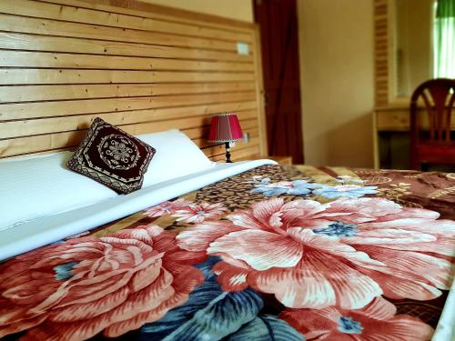 a bedroom with a bed with a flower quilt on it at Hotel Diplomat in Pokhara