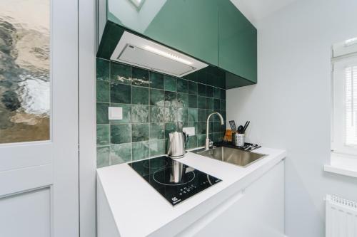 uma cozinha com um lavatório e azulejos verdes em Beautiful and Unique Apartment on the 3rd Floor-MEZZANINE em Cracóvia