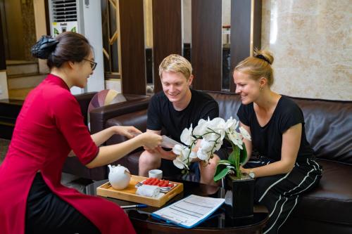 a woman is handing a man a box of flowers at Splendid Star Grand Hotel and Spa in Hanoi