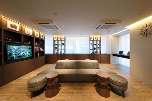 a living room with a couch and stools and a tv at Keio Presso Inn Tokyo Station Yaesu in Tokyo