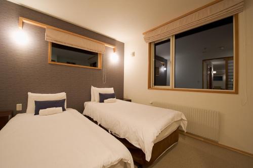 two beds in a small room with a window at Shinsetsu in Kutchan