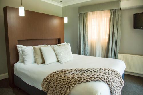 a hotel room with a large bed with white pillows at Peppers Craigieburn Resort in Bowral