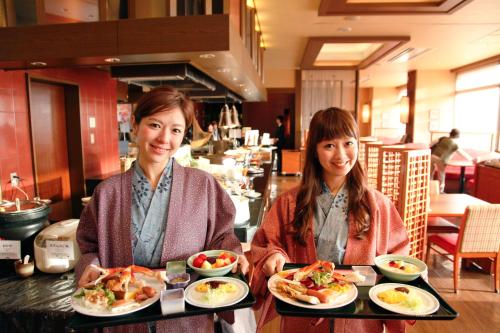two women sitting at a table with plates of food at Kotohira Grand Hotel Sakuranosho in Kotohira