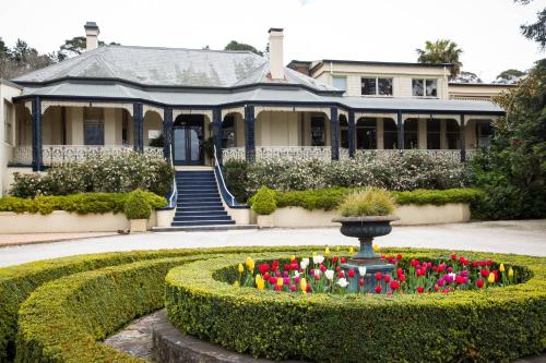 a house with a garden with a fountain and flowers at Peppers Craigieburn Resort in Bowral