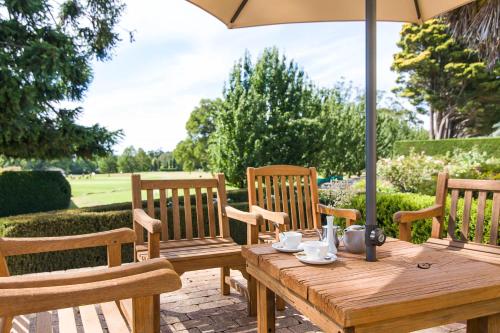 a wooden table and chairs under an umbrella at Peppers Craigieburn Resort in Bowral
